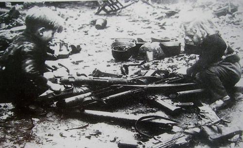 Berlinin küçələrindən birində atılmış silahlarla (tüfənglər, pulemyotlar) oynayan alman uşaqları